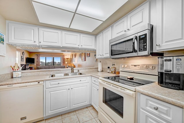 kitchen featuring light tile patterned flooring, sink, white cabinets, and white appliances