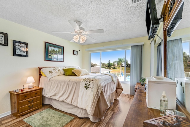 bedroom featuring ceiling fan, dark wood-type flooring, and a textured ceiling