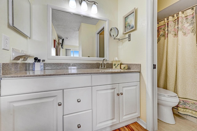 bathroom featuring tile patterned flooring, vanity, a textured ceiling, and toilet