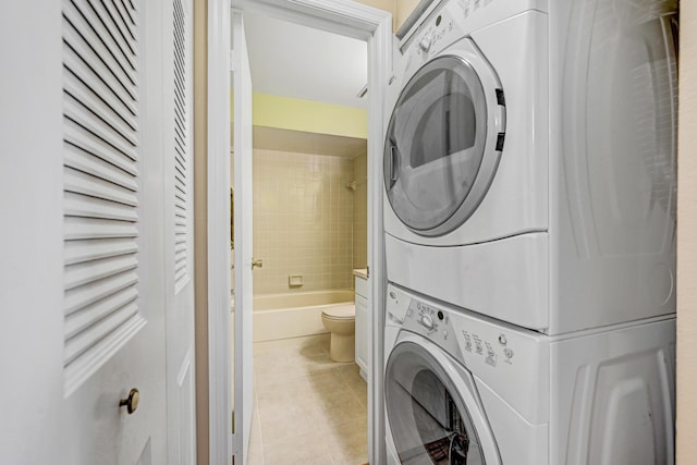 laundry area featuring light tile patterned flooring and stacked washer / dryer