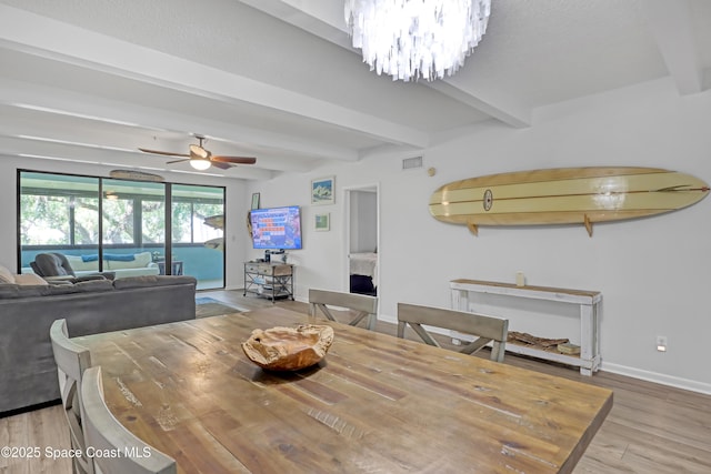 dining space with beamed ceiling, ceiling fan with notable chandelier, and hardwood / wood-style floors