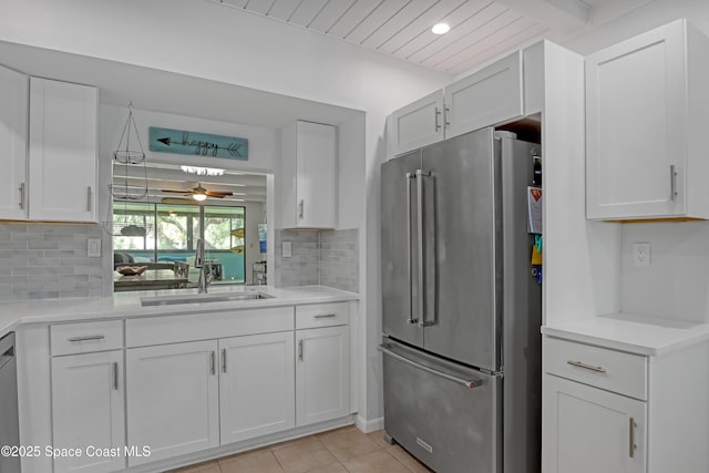 kitchen featuring light tile patterned flooring, sink, white cabinetry, stainless steel appliances, and backsplash