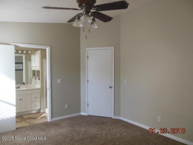 unfurnished bedroom featuring ceiling fan, connected bathroom, light carpet, and a textured ceiling