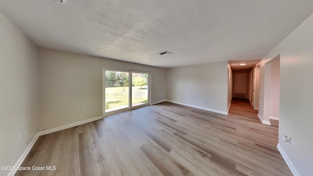 empty room with a textured ceiling and light wood-type flooring