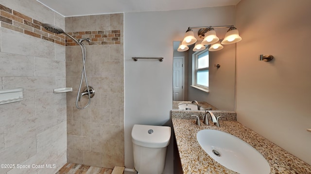 bathroom featuring vanity, tiled shower, and toilet