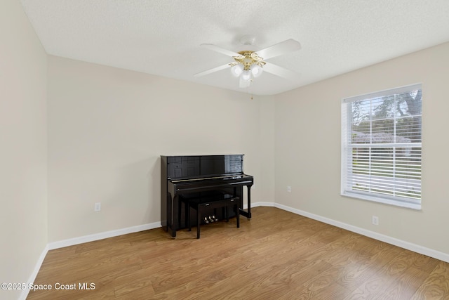 interior space featuring a textured ceiling, light wood-type flooring, and baseboards