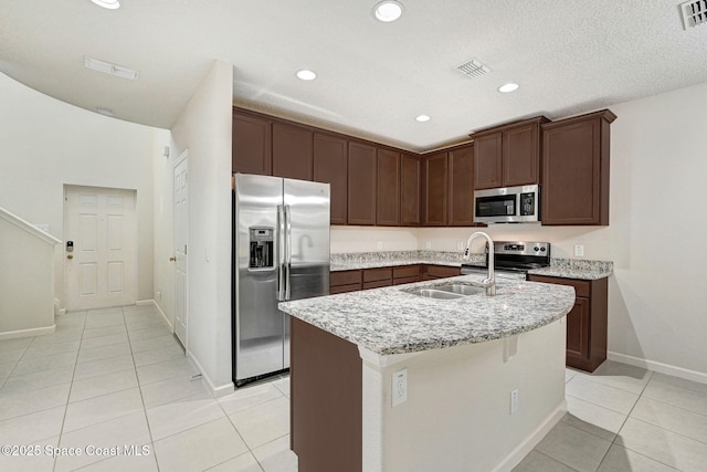 1425 Lara Cir Unit 103, Rockledge, FL 32955 - kitchen with stainless steel appliances, light tile patterned flooring, light stone counters, a kitchen island with sink, and recessed lighting