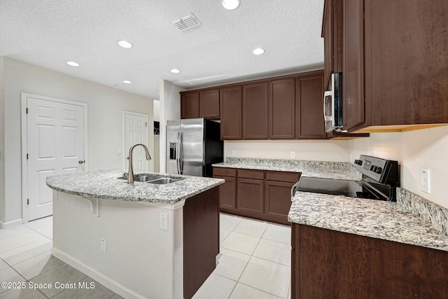 1425 Lara Cir Unit 103, Rockledge, FL 32955 - kitchen featuring appliances with stainless steel finishes, light tile patterned floors, an island with sink, light stone counters, and a textured ceiling