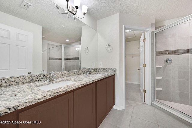 1425 Lara Cir Unit 103, Rockledge, FL 32955 - full bathroom featuring a shower stall, double vanity, a spacious closet, tile patterned flooring, and a textured ceiling