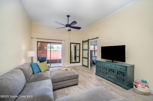 living area featuring a ceiling fan, crown molding, light wood-style flooring, and a barn door