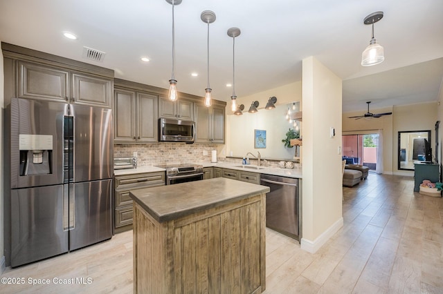 kitchen featuring a center island, a sink, stainless steel appliances, pendant lighting, and backsplash