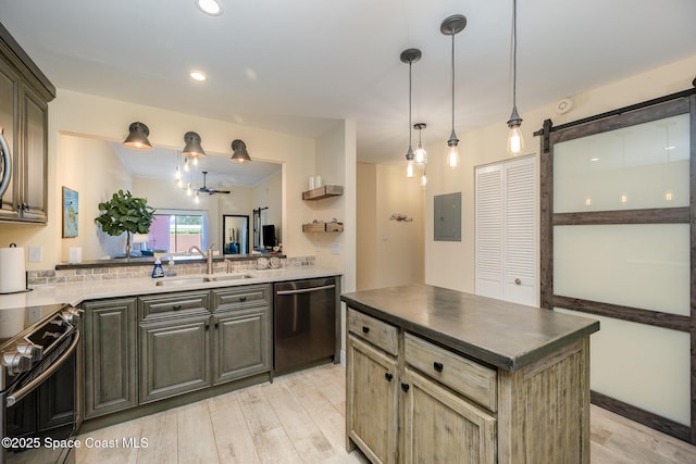 kitchen with light wood finished floors, a barn door, appliances with stainless steel finishes, a sink, and a kitchen island