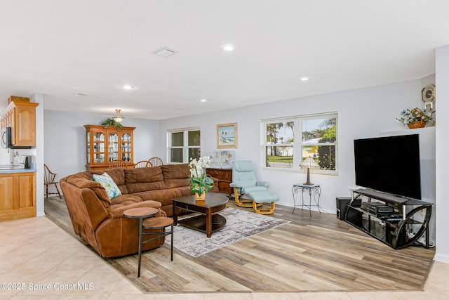 living room with light wood finished floors, baseboards, visible vents, and recessed lighting