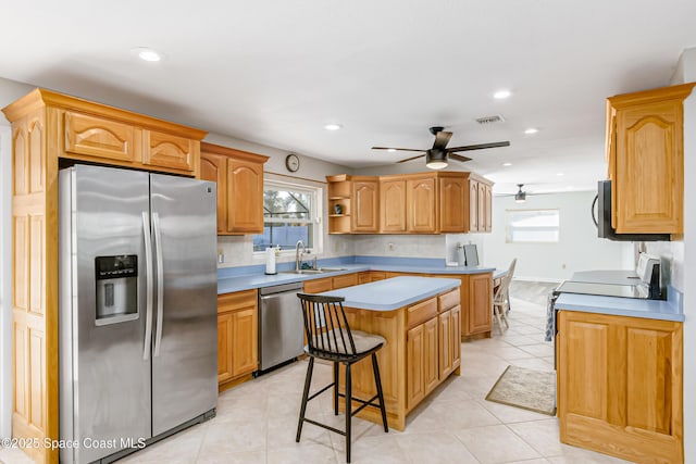 kitchen with a breakfast bar area, stainless steel appliances, light countertops, visible vents, and a kitchen island