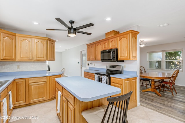 kitchen featuring recessed lighting, electric range, light countertops, a center island, and a kitchen bar