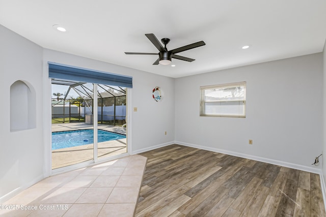 empty room featuring recessed lighting, a ceiling fan, a sunroom, wood finished floors, and baseboards