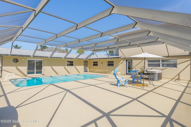 outdoor pool featuring glass enclosure and a patio area