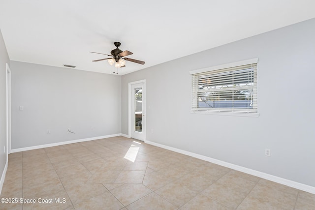 spare room with light tile patterned floors, a ceiling fan, visible vents, and baseboards