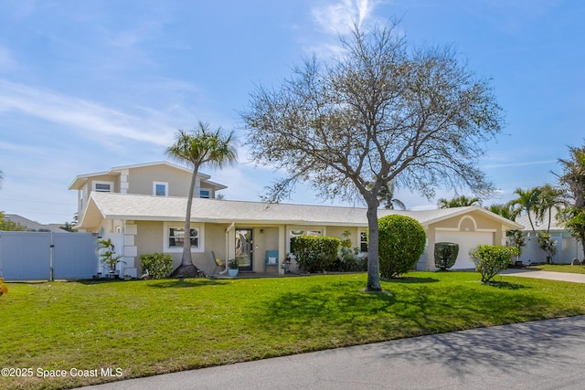 view of front of house featuring driveway, a garage, a gate, fence, and a front lawn