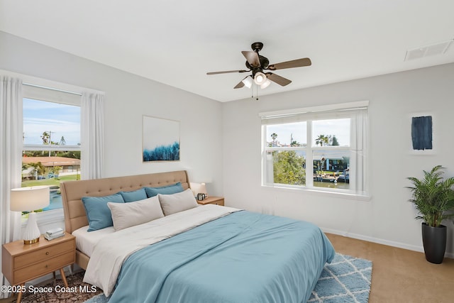 carpeted bedroom featuring baseboards, visible vents, and a ceiling fan