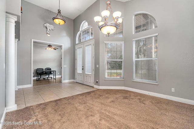 entrance foyer featuring ceiling fan with notable chandelier, light carpet, and a high ceiling