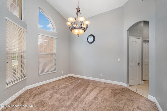 carpeted empty room with an inviting chandelier and a towering ceiling