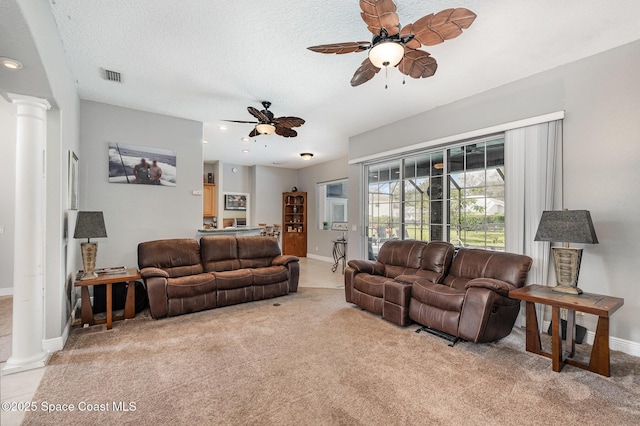 living room featuring ceiling fan, light colored carpet, decorative columns, and a textured ceiling