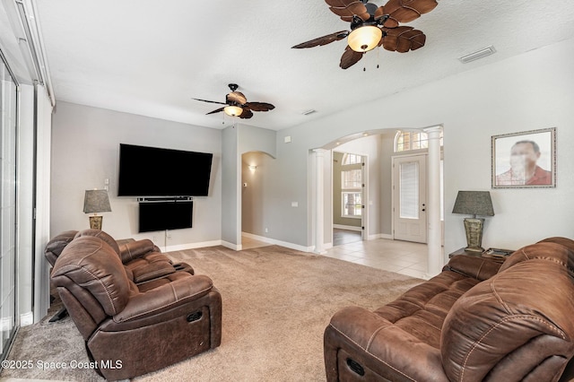 living room with light carpet, a textured ceiling, decorative columns, and ceiling fan