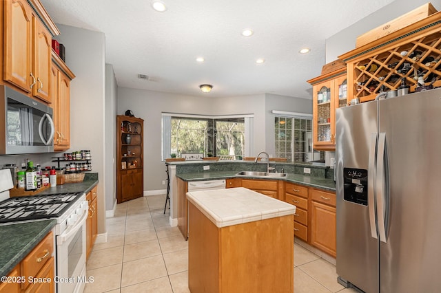 kitchen featuring sink, a center island, a textured ceiling, light tile patterned floors, and appliances with stainless steel finishes