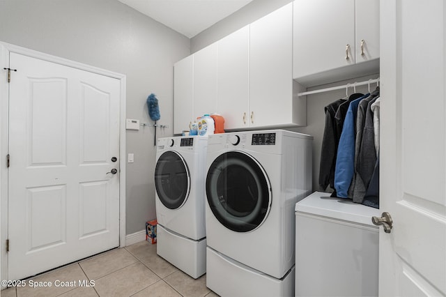 laundry room with light tile patterned floors, cabinets, and washing machine and clothes dryer