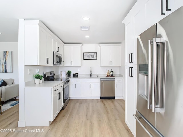 kitchen featuring sink, light wood-type flooring, white cabinets, and appliances with stainless steel finishes