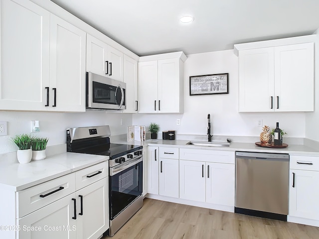 kitchen featuring white cabinetry, appliances with stainless steel finishes, sink, and light wood-type flooring