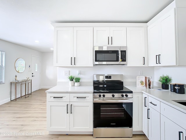 kitchen with white cabinetry, appliances with stainless steel finishes, and light hardwood / wood-style floors