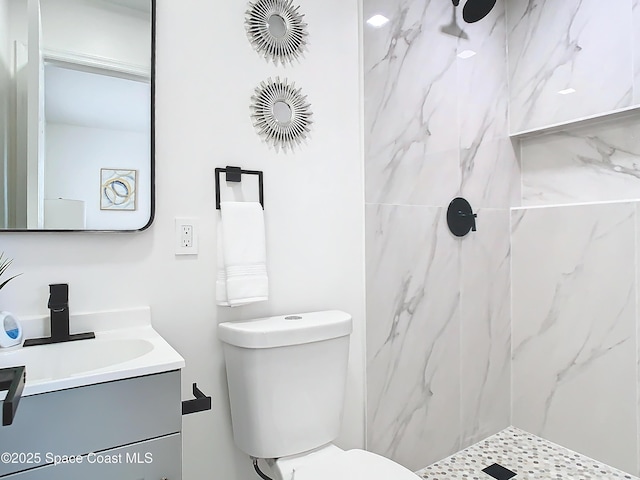 bathroom featuring vanity, toilet, and tiled shower