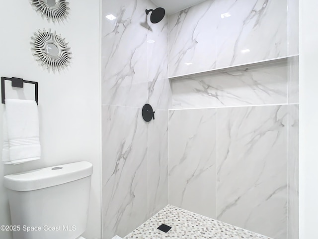 bathroom featuring a tile shower and toilet