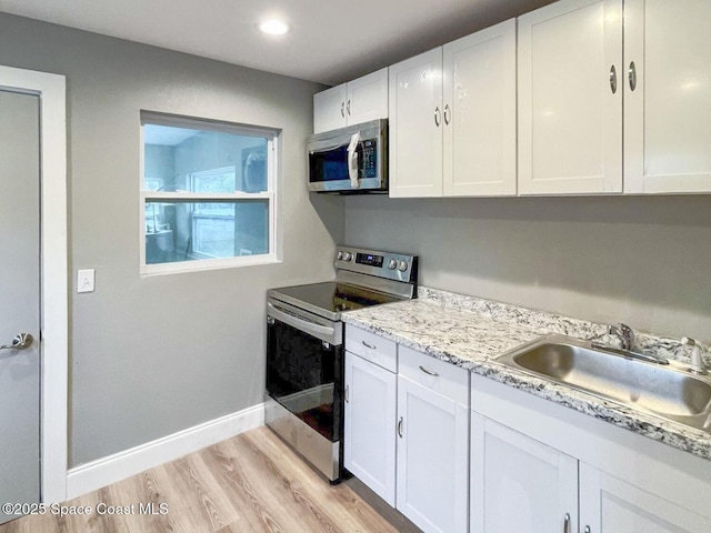 kitchen featuring sink, stainless steel appliances, light hardwood / wood-style floors, light stone countertops, and white cabinets