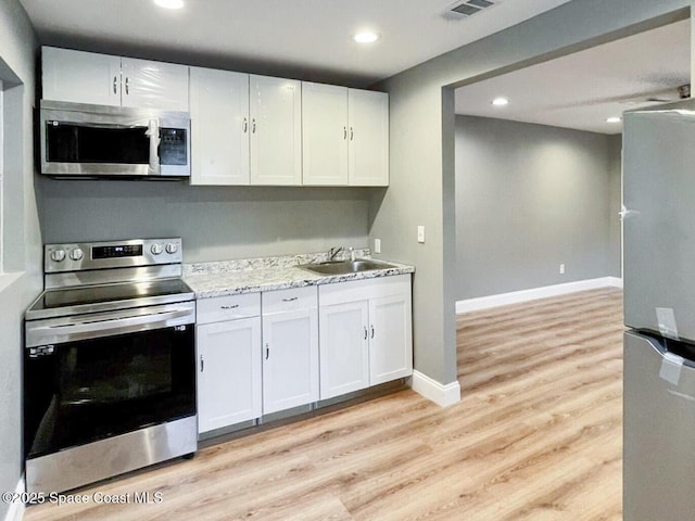 kitchen featuring light stone counters, stainless steel appliances, sink, and white cabinets