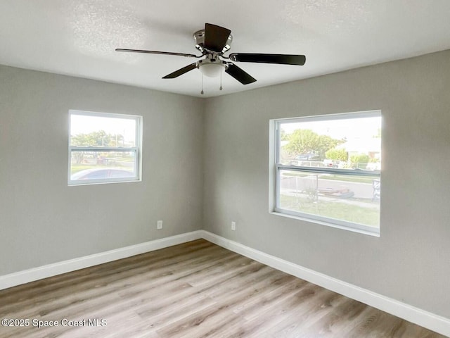 unfurnished room with a healthy amount of sunlight, a textured ceiling, and light wood-type flooring