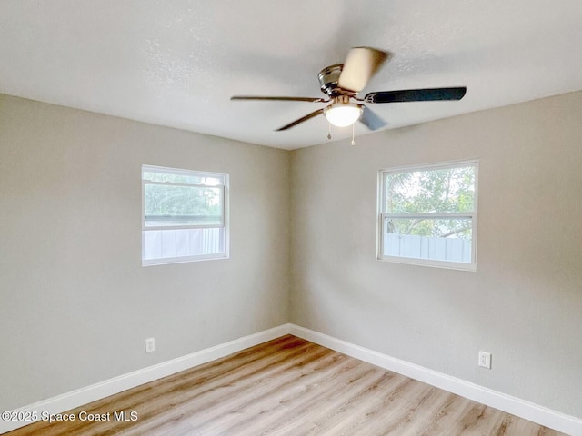 empty room with ceiling fan, plenty of natural light, and light hardwood / wood-style floors