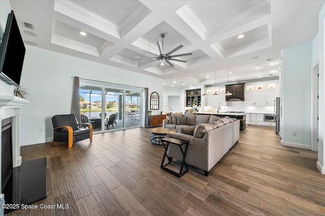living room featuring beam ceiling, ceiling fan, wood-type flooring, and coffered ceiling