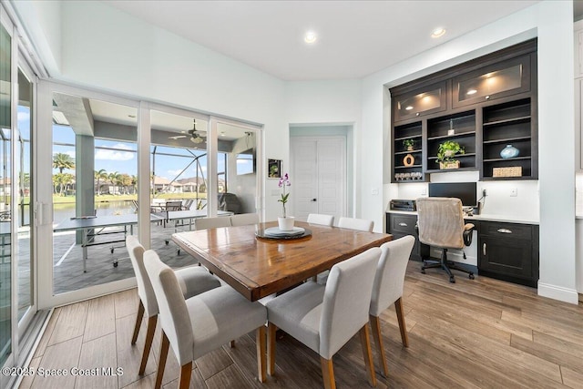 dining area featuring built in desk, ceiling fan, and light hardwood / wood-style flooring