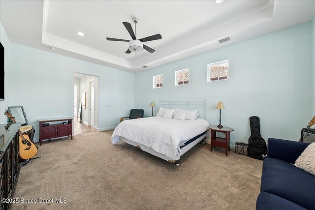 carpeted bedroom with a tray ceiling, ornamental molding, and ceiling fan