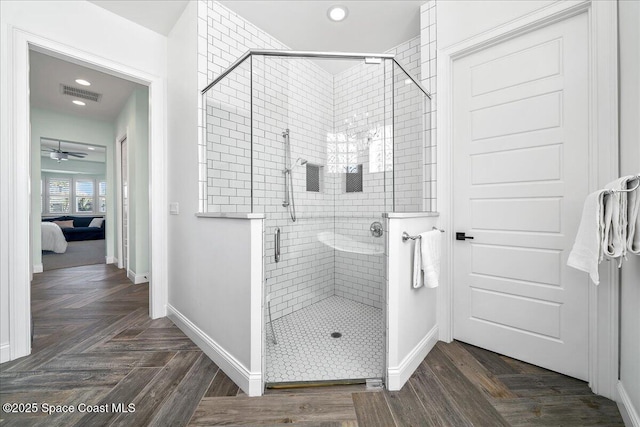 bathroom with hardwood / wood-style flooring, ceiling fan, and a shower with door