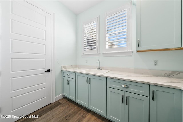 interior space with sink, dark wood-type flooring, and light stone countertops