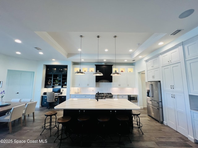 kitchen with a tray ceiling, a kitchen island, a kitchen bar, and premium appliances