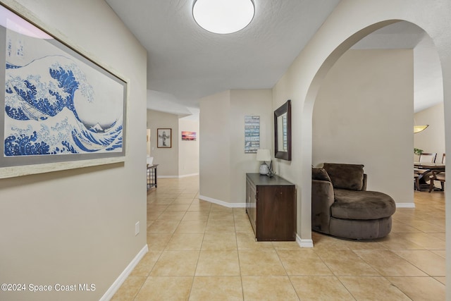 hall with light tile patterned floors and a textured ceiling