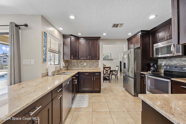 kitchen with light stone counters, sink, light tile patterned floors, and stainless steel appliances