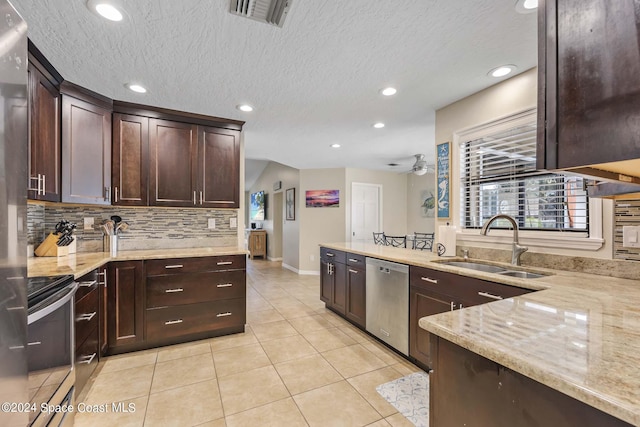 kitchen with sink, light tile patterned floors, appliances with stainless steel finishes, light stone countertops, and decorative backsplash