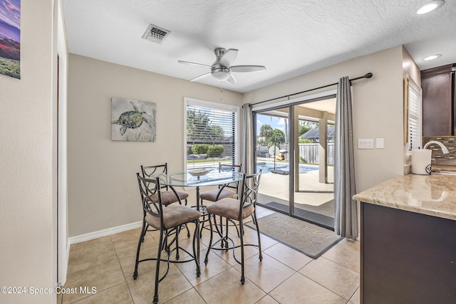 dining area with ceiling fan, a textured ceiling, and light tile patterned flooring