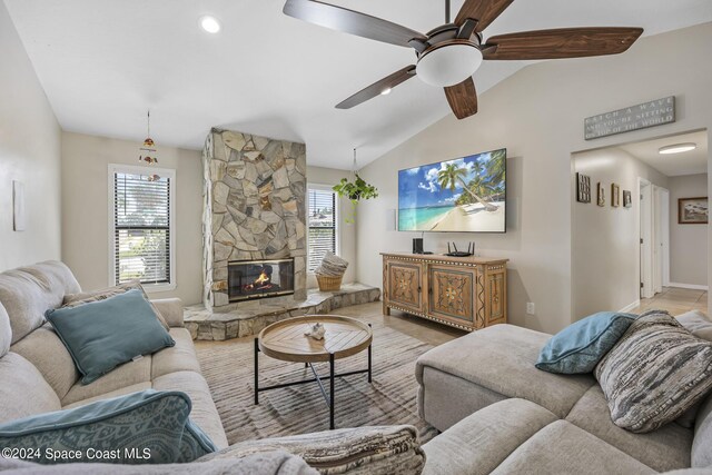 living room with ceiling fan, a fireplace, and vaulted ceiling